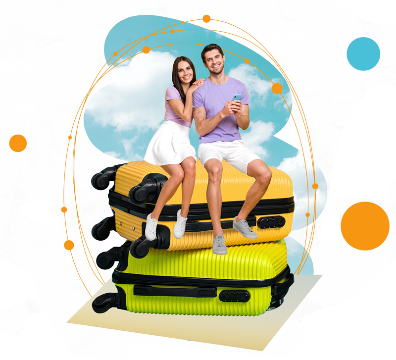 A joyful couple sitting on a stack of bright yellow and green suitcases against a cloudy sky background.